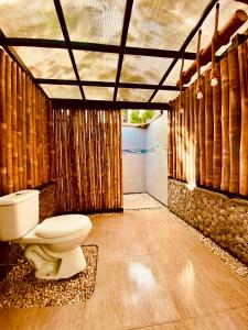 a bathroom with a toilet in a room with bamboo at Kanipa Beach Glamping in El Nido