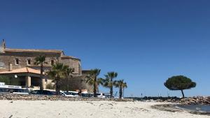 - un bâtiment sur la plage avec des palmiers et des voitures dans l'établissement 1Bed Cottage Sleeps 4- Sea Views Balcony Parking, à Mèze