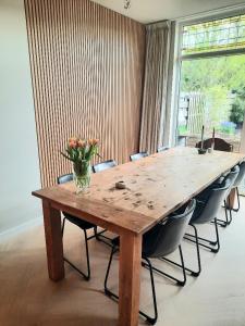 a wooden table with chairs and a vase of flowers on it at Zee-en-Zo Noordwijk in Noordwijk