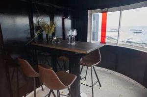 uma mesa com cadeiras e copos de vinho num quarto em Lofoten Fyr em Værøy