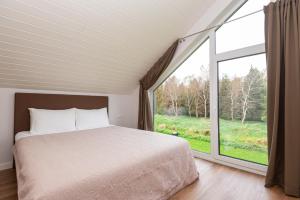 a bedroom with a bed and a large window at KUTI apartamentai in Palanga