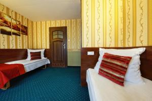 2 camas en una habitación con papel pintado de color amarillo en Noclegi I Restauracja Zodiak, en Gliwice