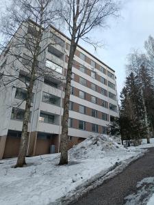 a building in the snow next to two trees at Mukkula apartment Lahti 59 m2 in Lahti