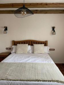 Una cama con sábanas blancas y almohadas en un dormitorio en El Capricho de la Serranía I en Tragacete