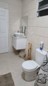 a white bathroom with a toilet and a sink at Welcome to our 1 bedroom villa in Bridgetown