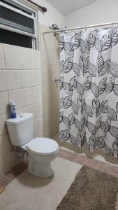a bathroom with a toilet and a shower curtain at Welcome to our 1 bedroom villa in Bridgetown