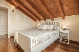 una camera con letto bianco e soffitto in legno di Attico Borromea a Leggiuno