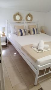 ein weißes Bett mit Kissen auf dem Zimmer in der Unterkunft Sea Breeze in Archangelos