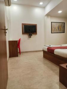 a bedroom with a bed and a tv on a wall at Hotel Beach Crown Juhu in Mumbai