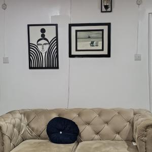 J Lounge في Ikorodu: أريكة في غرفة معيشة مع صور على الحائط