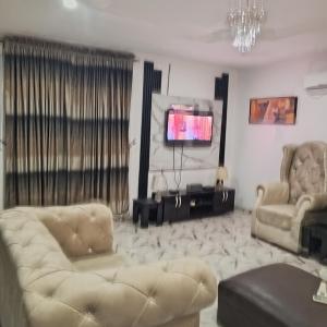 J Lounge في Ikorodu: غرفة معيشة مع كرسيين وتلفزيون