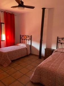 a bedroom with two beds and a ceiling fan at Casa Rural La Encina in Azuel