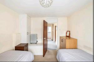 1 dormitorio con 2 camas y espejo en London Stratford Holiday Home, en Londres