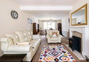 sala de estar con 2 sillas blancas y chimenea en London Stratford Holiday Home en Londres