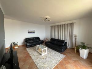 ein Wohnzimmer mit einer schwarzen Couch und einem Tisch in der Unterkunft Spring House AL in Arco da Calheta