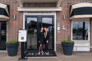 dos mujeres de pie en la puerta de un edificio en Restaurant & Hotel Monopole Harderwijk, en Harderwijk