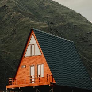 a house with a green mountain in the background at MOUNTAIN CABIN in Ushguli