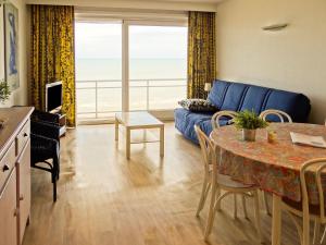 uma sala de estar com um sofá azul e uma mesa em Scorpio B1004 with beautiful sea views em Nieuwpoort