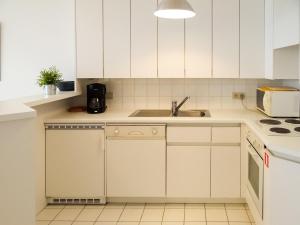 uma cozinha com armários brancos e um lavatório em Scorpio B1004 with beautiful sea views em Nieuwpoort