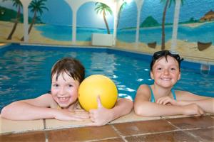 zwei Kinder in einem Pool mit Ball in der Unterkunft Ferien- und Reitsport Hotel Brunnenhof in Suhlendorf