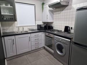 a kitchen with a washing machine and a sink at Contemporary City Centre Flat in Belfast