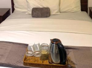 a tray with a tea kettle and glasses on a bed at Khaya Mnandi Leisure Suites in Pretoria +10 photos