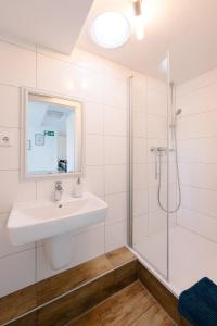 La salle de bains est pourvue d'un lavabo et d'une douche. dans l'établissement GästeHaus am Flughafen Düsseldorf, à Düsseldorf