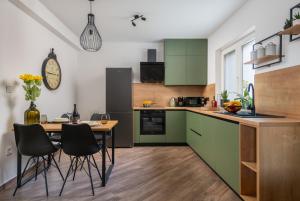 una cocina con armarios verdes, mesa y sillas en Green Nest, ground floor apt with garden & garage, en Medulin