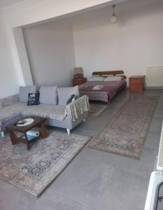 sala de estar con sofá, cama y alfombras en GÜLBEYAZ PANSİYON, en Dikili