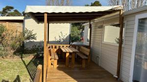 a wooden deck with a picnic table and an awning at Mobil-home - Narbonne-Plage - Clim, TV in Narbonne-Plage