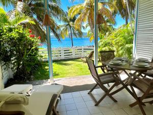 - une terrasse couverte avec une table et des chaises et l'océan dans l'établissement Bungalow Sucrier, les pieds dans l'eau, à Terre-de-Haut