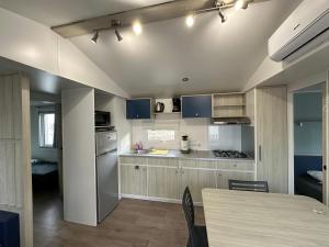 a kitchen with a table and a kitchen with blue cabinets at Mobil-home - Narbonne-Plage - Clim, TV in Narbonne-Plage