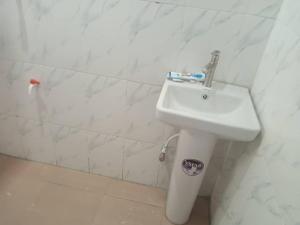 La salle de bains est pourvue d'un lavabo et d'un mur blancs. dans l'établissement Tradebybata Homes, Abeokuta around FUNAAB, à Abeokuta