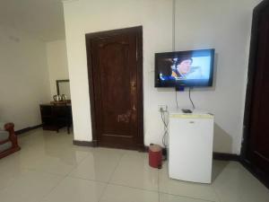 a room with a tv on the wall and a refrigerator at Khaya Mnandi Leisure Suites in Pretoria
