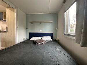 a bed in a room with a large window at Mobil-home - Narbonne-Plage - Clim, TV in Narbonne-Plage