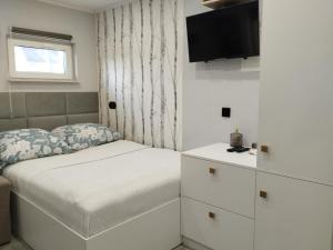 um pequeno quarto com uma cama e uma televisão em Mały Domek Klimatyzacja, Aneks Kuchenny, Parking em Bodzanów