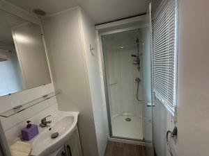 a white bathroom with a shower and a sink at Mobil-home - Narbonne-Plage - Clim, TV in Narbonne-Plage