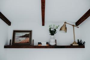 a shelf with a vase of flowers and a lamp at Cozy & Thoughtful Tiny Home in Kallangur