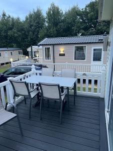 a deck with a table and chairs and a house at Luxury modern caravan Seton Sands in Port Seton
