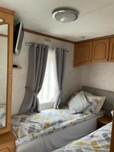 a bed in a small room with a window at Luxury modern caravan Seton Sands in Port Seton