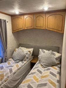 two beds in a small room with wooden cabinets at Luxury modern caravan Seton Sands in Port Seton