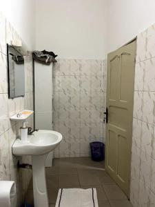 a bathroom with a sink and a mirror and a door at Appartement spacieux bien situé in Cotonou