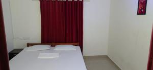 um quarto com uma cama e uma cortina vermelha em NEW OCEAN EYES RESIDENCY em Varkala