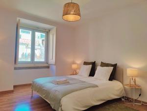 una camera da letto con un letto con due lampade e una finestra di Apartmento com vista incrivel a Lisbona