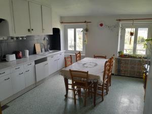 una cocina con mesa y sillas y una cocina con armarios blancos. en hOMe-Shanti Galamus en Saint-Paul-de-Fenouillet