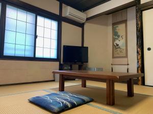 a living room with a wooden table and a tv at Iya Kankou Ryokan in Miyoshi