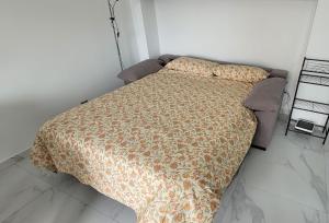 ein Bett mit einer Bettdecke in einem Schlafzimmer in der Unterkunft Cómodo apartamento en Playa Gandia in Los Mártires