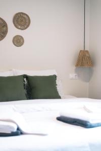 a white bed with a green pillow and a lamp at To Patriko in Kournás