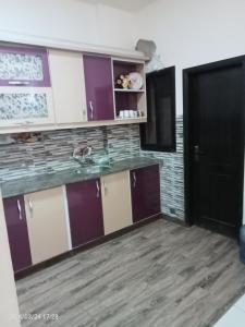 a kitchen with purple and white cabinets and a black door at Luxury Apartment in Karachi