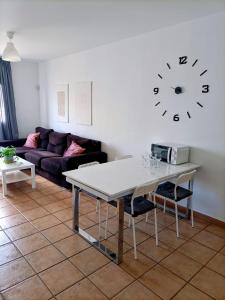 een woonkamer met een tafel en een klok aan de muur bij Capital House 2 in Arrecife